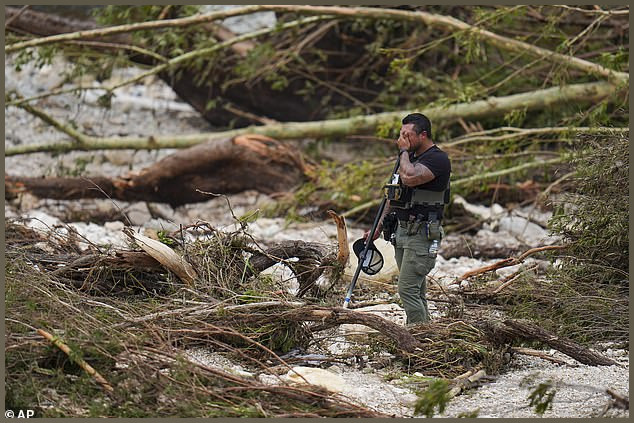 A first responder appears emotional amid the ongoing searched, with over 100 bodies found in flood waters including at least 36 children